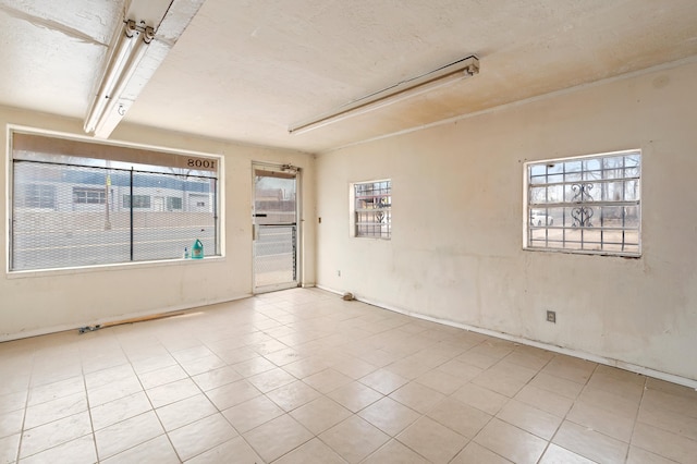 unfurnished room with tile patterned flooring, a textured ceiling, and a wealth of natural light