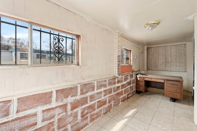 interior space featuring tile patterned flooring and brick wall