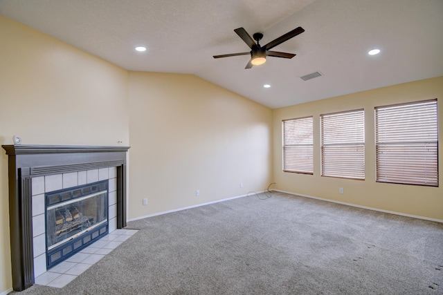 unfurnished living room with baseboards, visible vents, a tiled fireplace, vaulted ceiling, and carpet floors