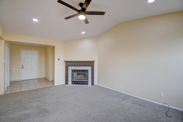 unfurnished living room featuring light carpet, a tiled fireplace, lofted ceiling, and recessed lighting