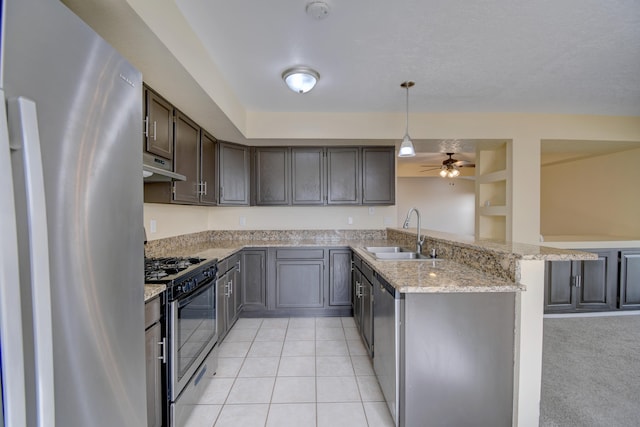 kitchen featuring light stone counters, under cabinet range hood, a peninsula, a sink, and appliances with stainless steel finishes