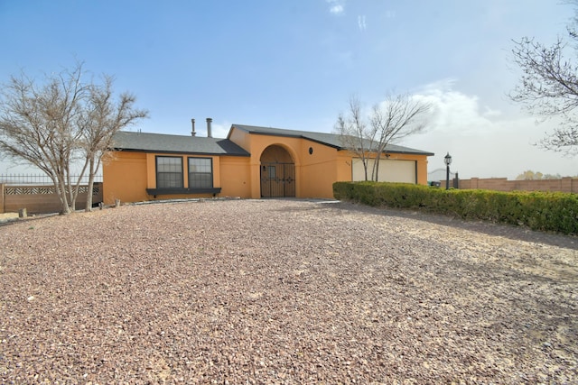 view of front of home with an attached garage, fence, and stucco siding