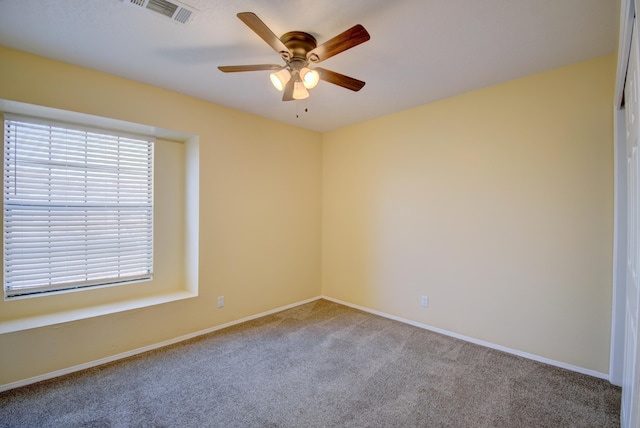 spare room featuring ceiling fan, carpet flooring, visible vents, and baseboards