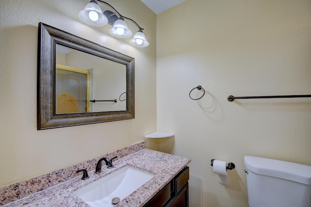 bathroom with toilet, a shower with shower door, and vanity