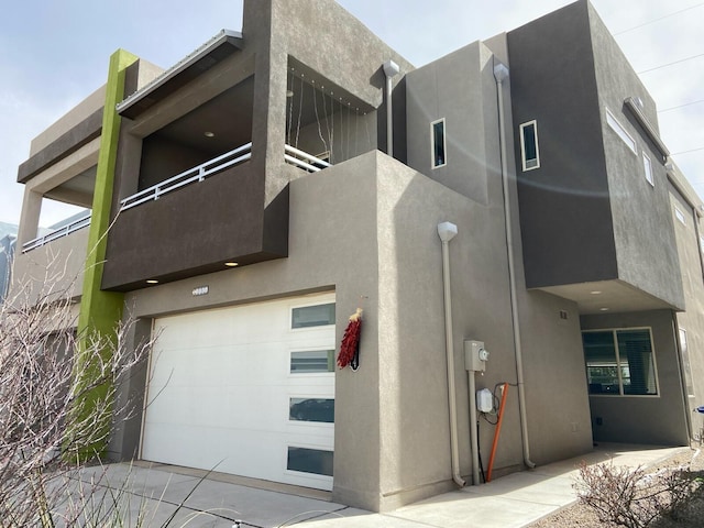 exterior space with an attached garage, a balcony, and stucco siding