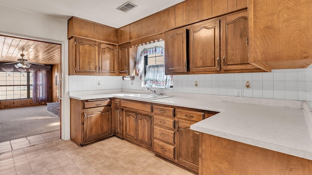 kitchen with visible vents, light colored carpet, brown cabinets, light countertops, and a sink