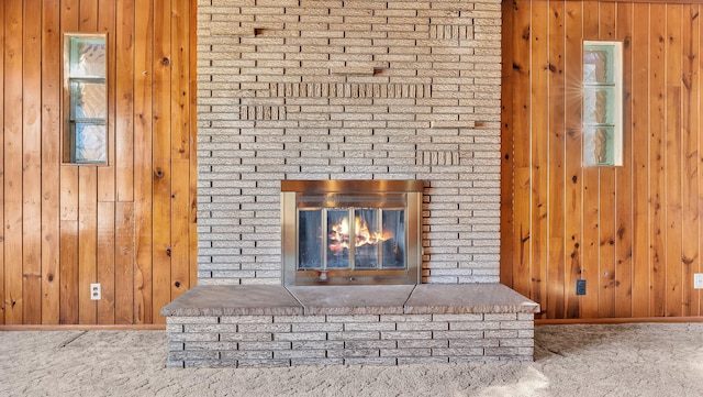 details featuring a brick fireplace, carpet flooring, and wood walls