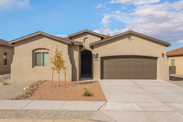 view of front of house with a garage, concrete driveway, and stucco siding