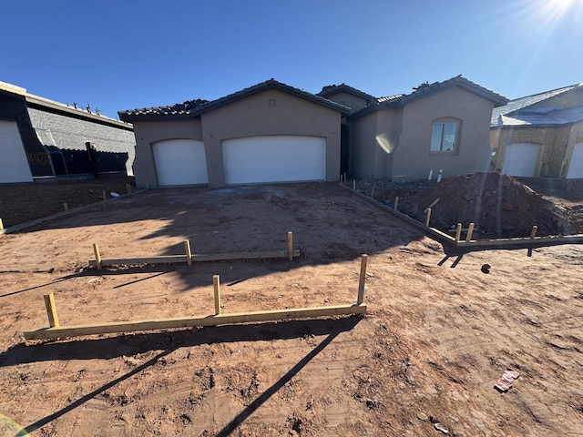 mediterranean / spanish-style house featuring driveway, a tiled roof, a garage, and stucco siding