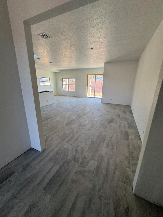 unfurnished room featuring a textured ceiling, visible vents, and wood finished floors