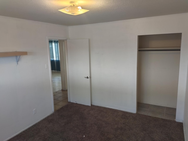 unfurnished bedroom with tile patterned floors, a closet, carpet, and a textured ceiling