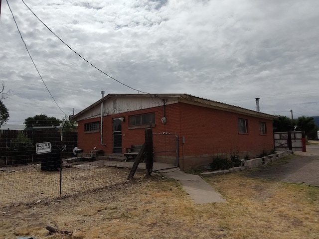 view of home's exterior with a patio, fence, and brick siding