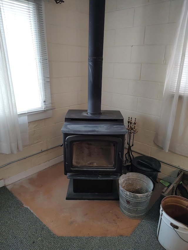 interior details with concrete flooring, concrete block wall, and a wood stove