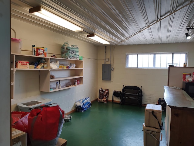 miscellaneous room featuring concrete block wall, electric panel, finished concrete flooring, and a garage