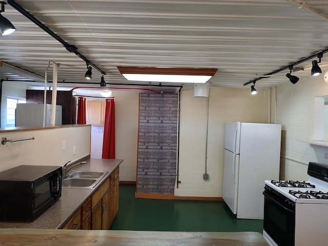 kitchen with black microwave, range with gas stovetop, brown cabinets, freestanding refrigerator, and a sink