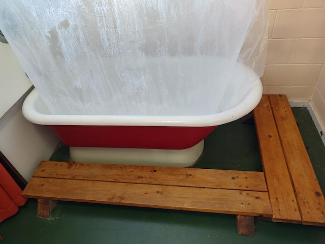 full bathroom featuring a freestanding tub and concrete block wall