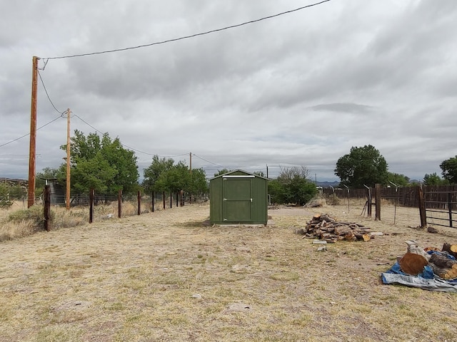 view of yard featuring a storage shed, fence, and an outdoor structure