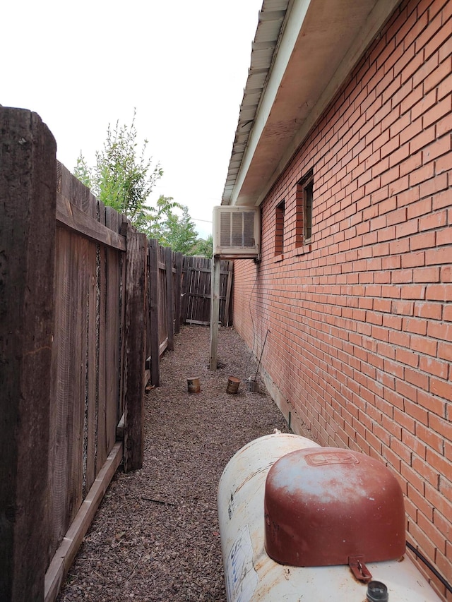 view of property exterior with brick siding, central AC, and a fenced backyard