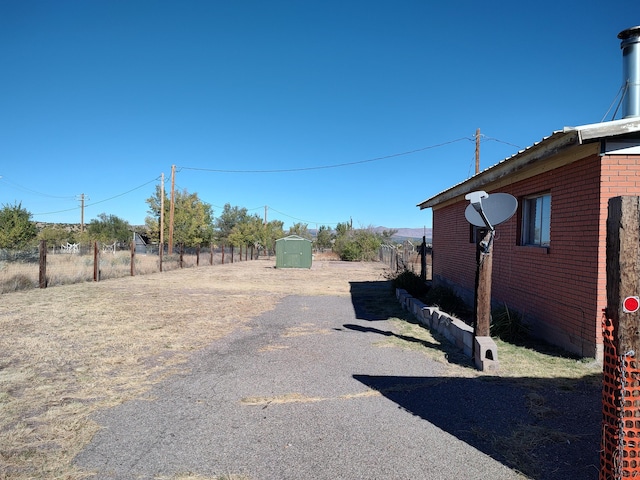 view of yard featuring a storage unit, an outdoor structure, and fence