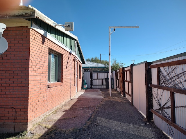 view of side of home with fence and brick siding