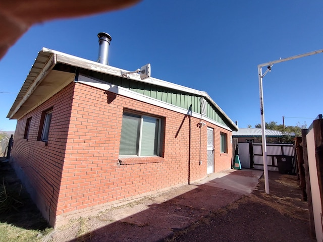 view of home's exterior featuring brick siding, board and batten siding, and fence