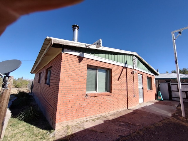 view of side of property featuring brick siding, board and batten siding, and fence