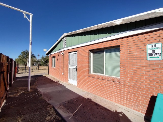 view of side of property with board and batten siding, fence, and brick siding