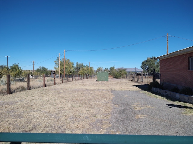 view of yard featuring an outbuilding, a storage unit, and fence