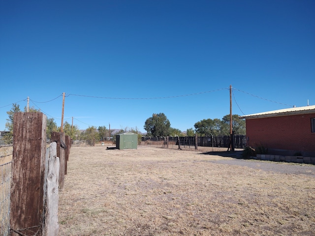 view of yard with an outbuilding, fence, and a shed