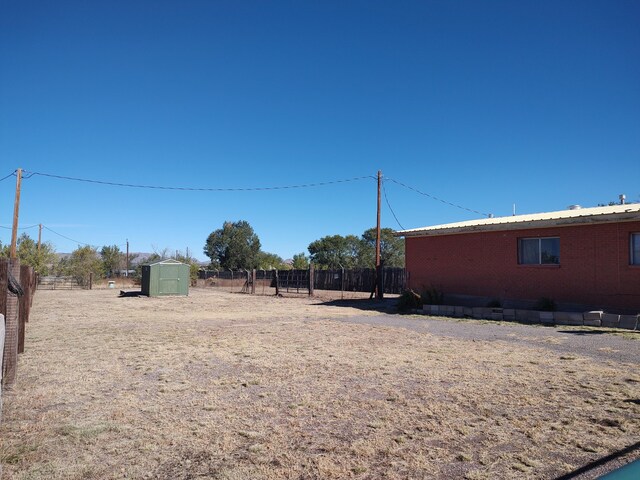 view of yard featuring an outbuilding, a shed, and fence