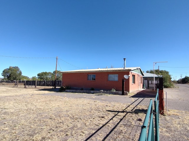 view of side of home with metal roof and fence