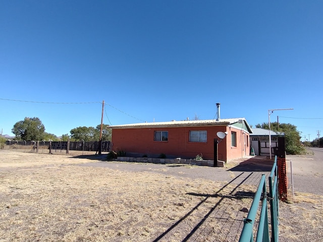 view of side of property featuring metal roof and fence