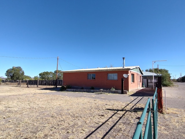 view of side of home featuring metal roof and fence