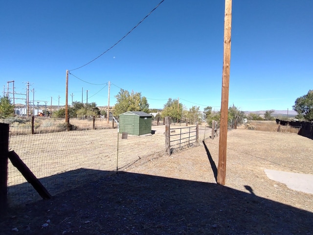 view of yard featuring a storage unit, an outdoor structure, and fence