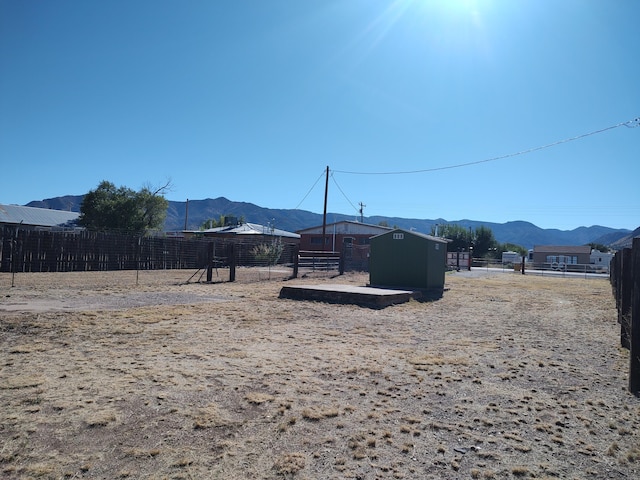 view of yard with a mountain view, an outbuilding, and fence