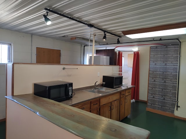 kitchen featuring open shelves, rail lighting, black microwave, and a sink