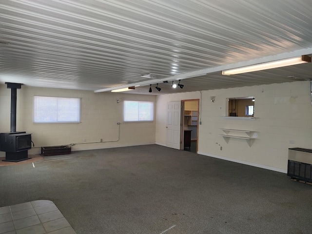 garage featuring heating unit, concrete block wall, and a wood stove