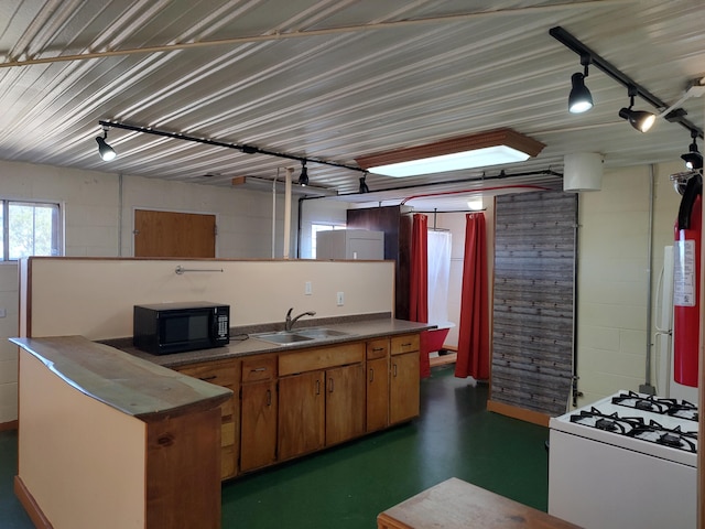 kitchen featuring a sink, gas range gas stove, dark countertops, concrete floors, and black microwave