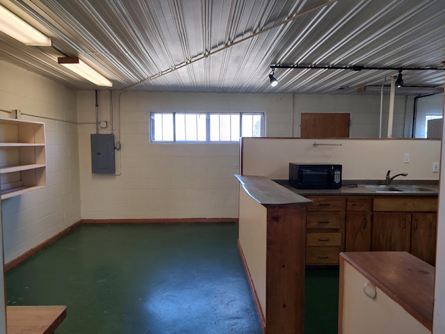 basement with concrete block wall, electric panel, and a sink