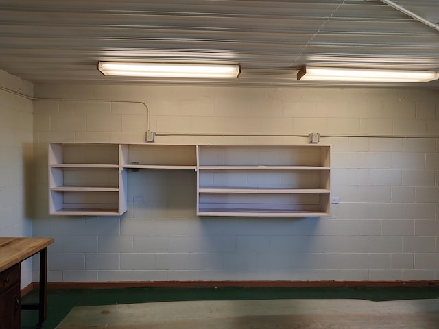 interior space featuring open shelves, concrete block wall, and concrete flooring