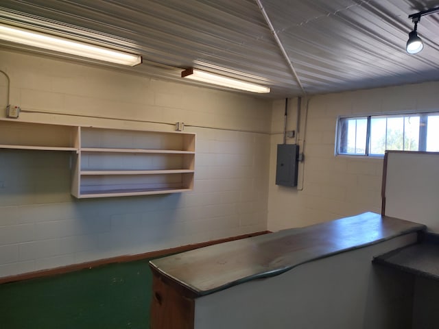 unfurnished office featuring concrete block wall and electric panel