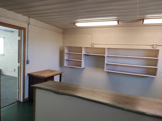 kitchen with open shelves, concrete block wall, and butcher block countertops