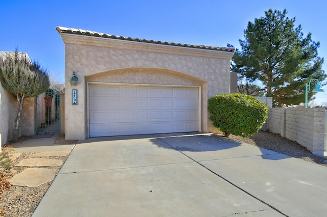 garage featuring driveway and fence