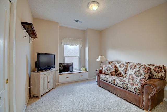 living area featuring baseboards, light carpet, visible vents, and a textured ceiling