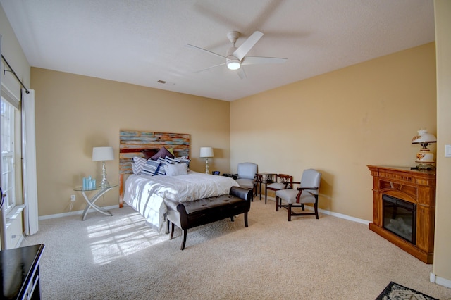 bedroom featuring a ceiling fan, baseboards, carpet flooring, and a glass covered fireplace