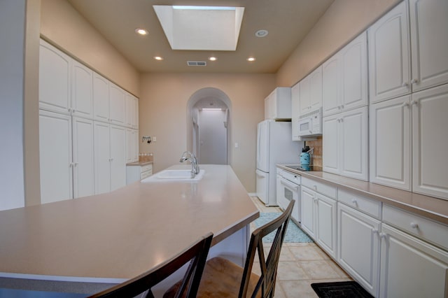 kitchen with white appliances, arched walkways, a sink, and recessed lighting