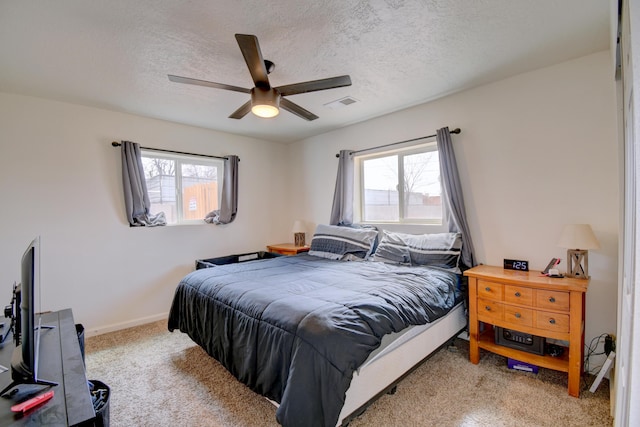 carpeted bedroom featuring a textured ceiling, multiple windows, visible vents, and baseboards