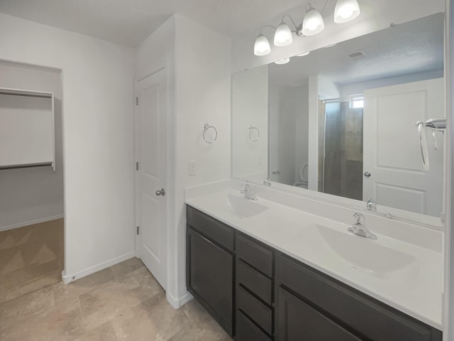 full bath featuring a stall shower, a sink, baseboards, and double vanity