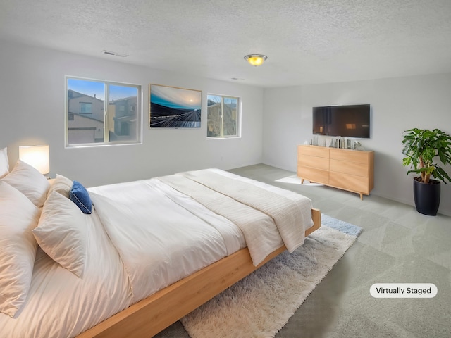 bedroom featuring a textured ceiling, carpet flooring, and visible vents