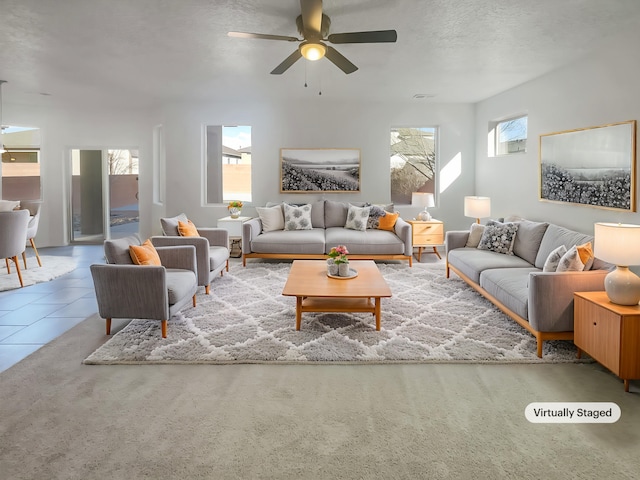 carpeted living room with a textured ceiling, plenty of natural light, a ceiling fan, and tile patterned floors